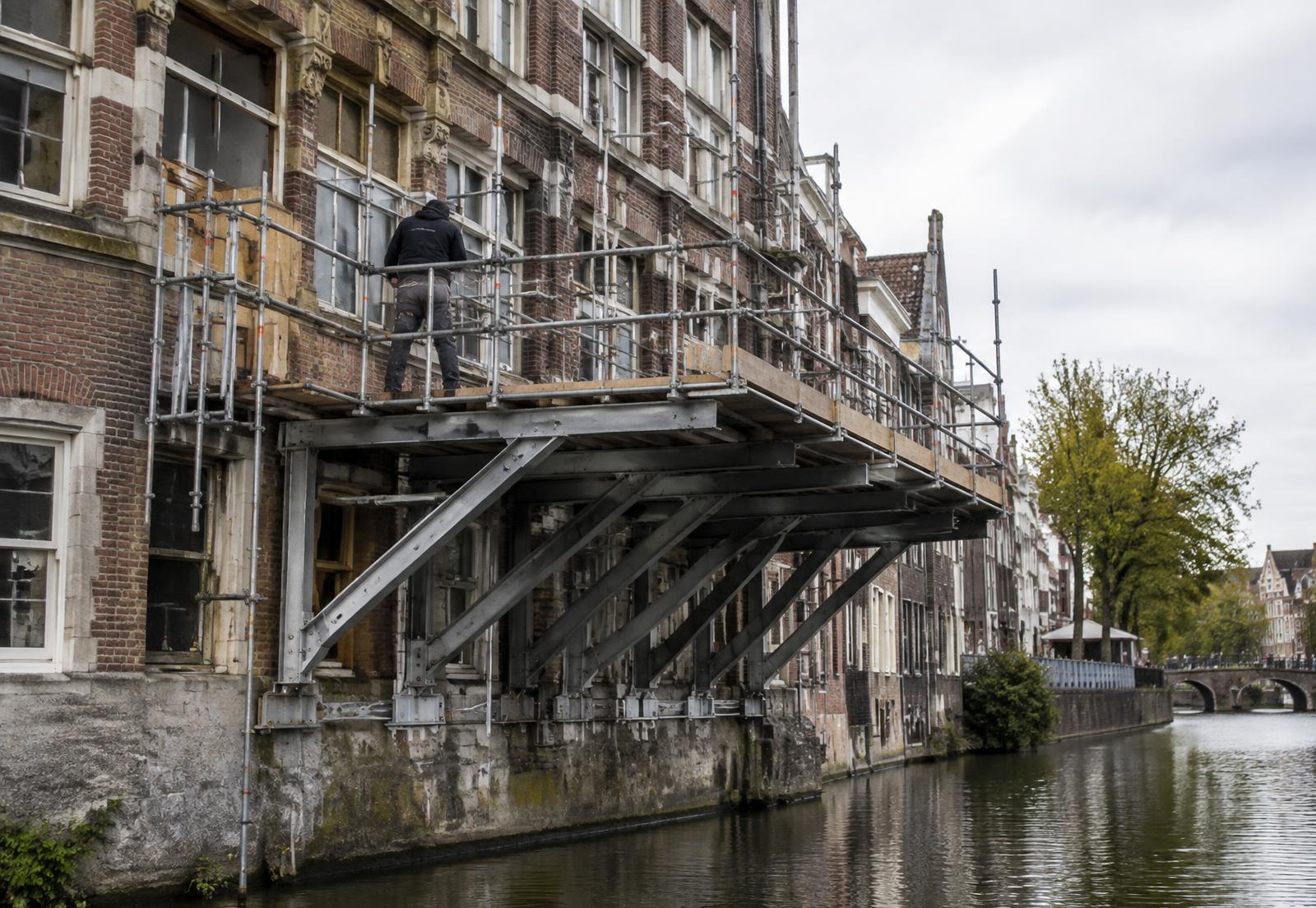 Uitgebouwde steigerconstructie langs een gevel boven het water